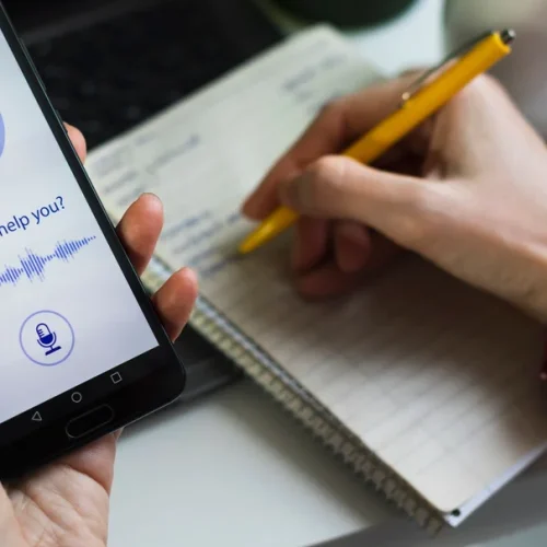 Usuário interage com assistente virtual pelo celular enquanto organiza suas tarefas — exemplo prático de como prompts simples de IA ajudam no dia a dia.