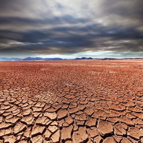 Solo seco e rachado sob céu ameaçador revela os efeitos extremos das mudanças climáticas — um alerta visual para o futuro que já chegou.