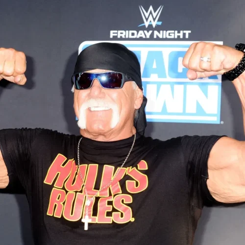 Hulk Hogan posa para fotos no evento Friday Night SmackDown da WWE, exibindo seu visual clássico com a camiseta "Hulk's Rules" e seu tradicional gesto de força.