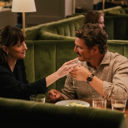 Lucy (Dakota Johnson) compartilha um jantar tenso com um dos homens que orbitam sua vida emocional — cena do filme Amores Materialistas, onde cada gesto carrega o peso de escolhas amorosas e financeiras.