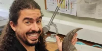 Após receber alta hospitalar, o biólogo e divulgador científico Pirulla retorna aos estudos com garra — literalmente. A imagem mostra o youtuber em seu ambiente de pesquisa, segurando uma impressionante garra fóssil.